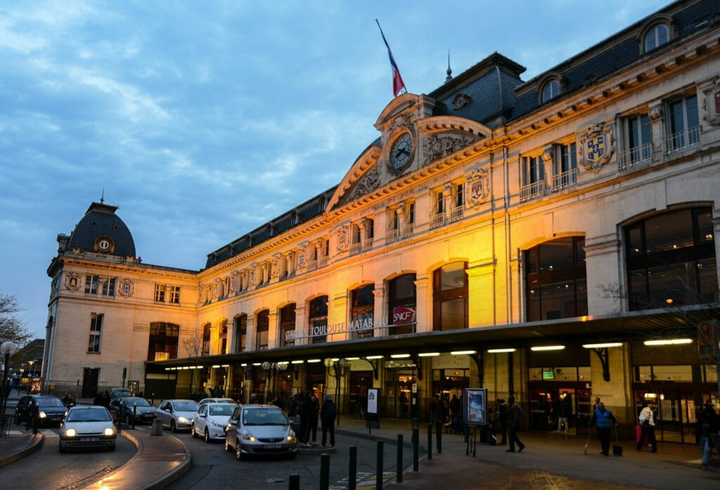 Façade éclairée de la gare Matabiau à Toulouse, à la tombée du jour